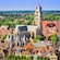 A large Gothic cathedral in a town with trees and historical buildings